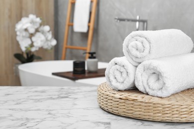 Photo of Rolled bath towels on white marble table in bathroom, space for text