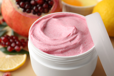 Jar of facial mask and fresh pomegranate on beige background, closeup. Natural organic cosmetics