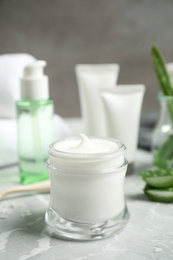 Photo of Open jar of aloe cream on grey marble table. Organic cosmetics