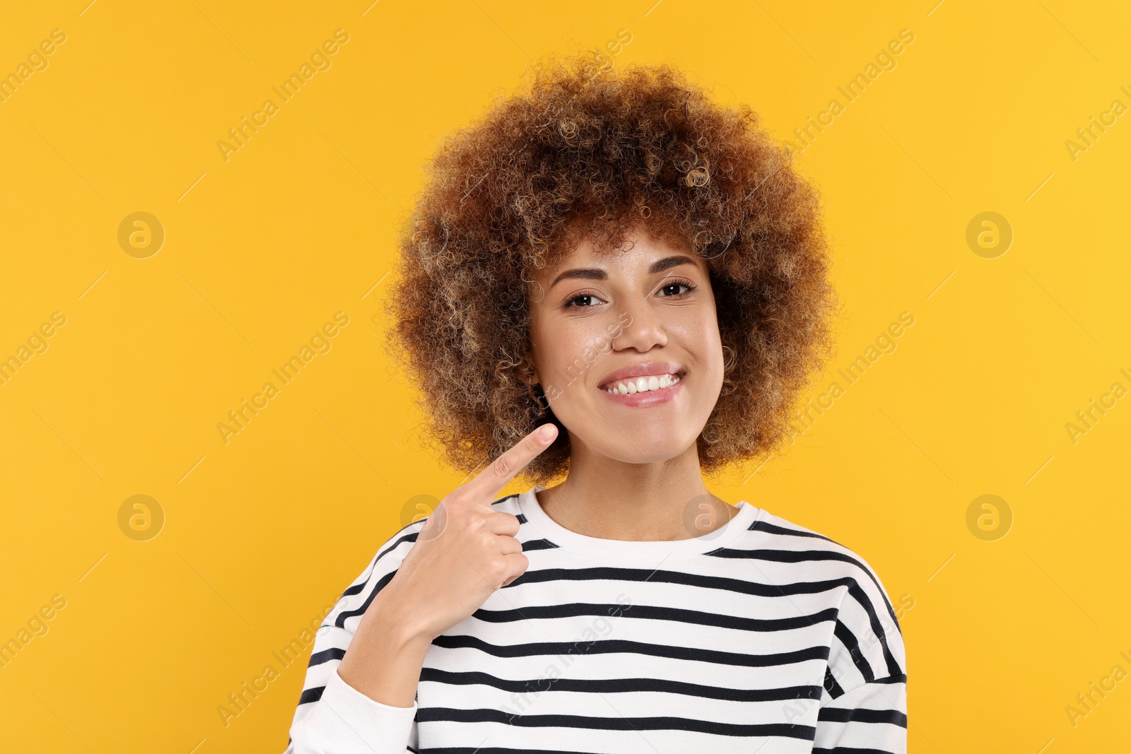 Photo of Woman showing her clean teeth on yellow background