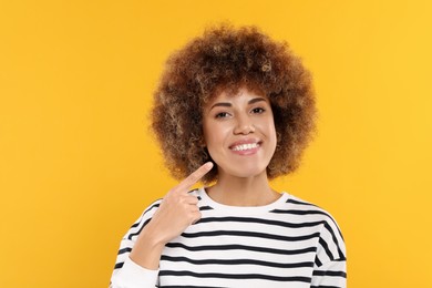Woman showing her clean teeth on yellow background