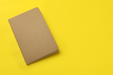 Photo of New stylish kraft planner on yellow background, top view. Space for text