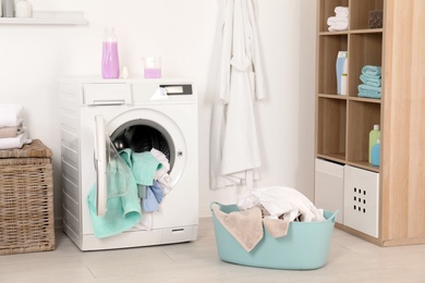 Photo of Washing machine with dirty clothes and towels in laundry room