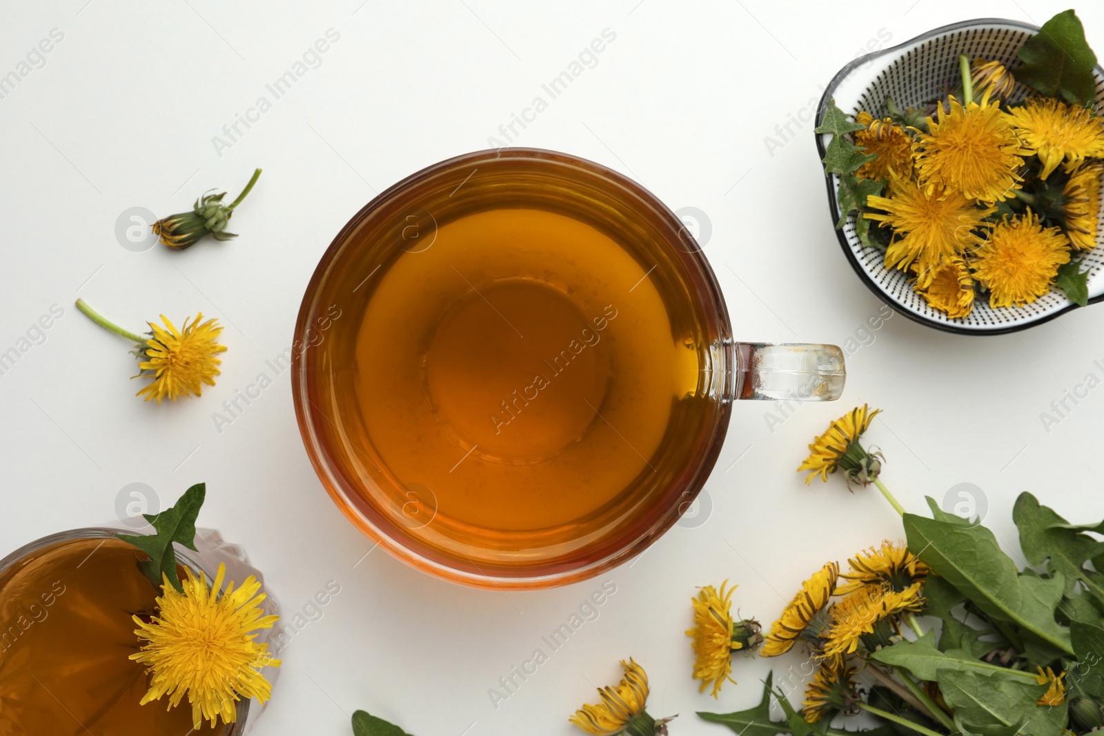 Photo of Delicious fresh tea and beautiful dandelion flowers on white background, top view