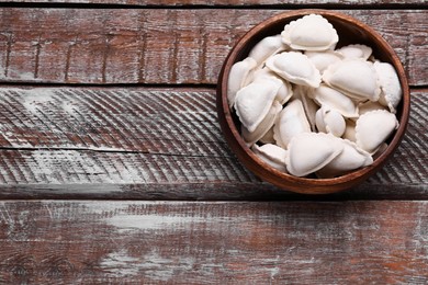 Raw dumplings (varenyky) on wooden table, top view. Space for text