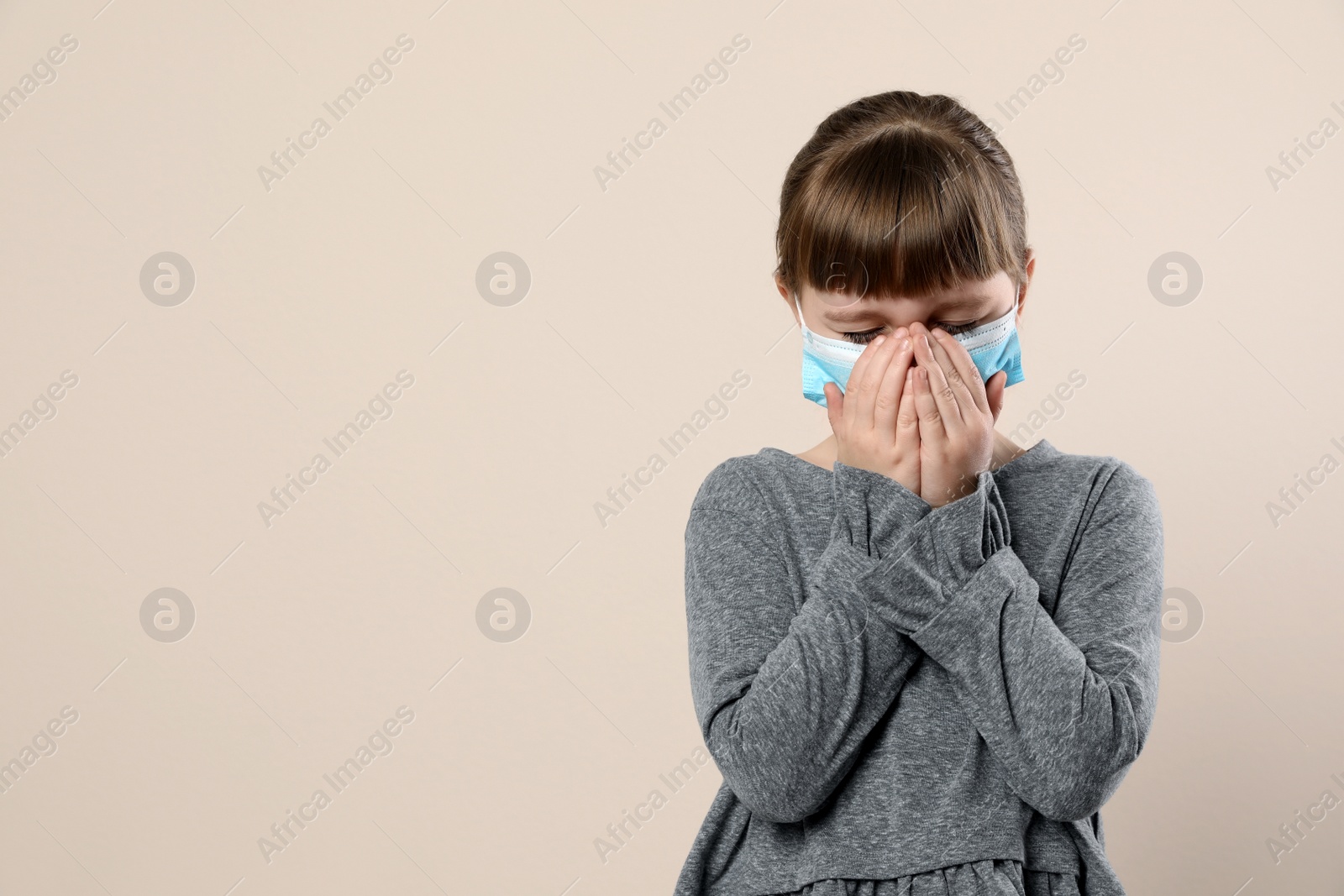 Photo of Little girl in medical mask on beige background, space for text. Virus protection