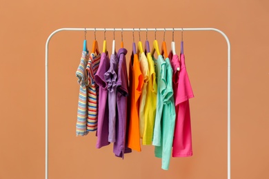 Rack with stylish children clothes on beige background