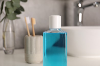 Photo of Bottle of mouthwash on white countertop in bathroom, closeup