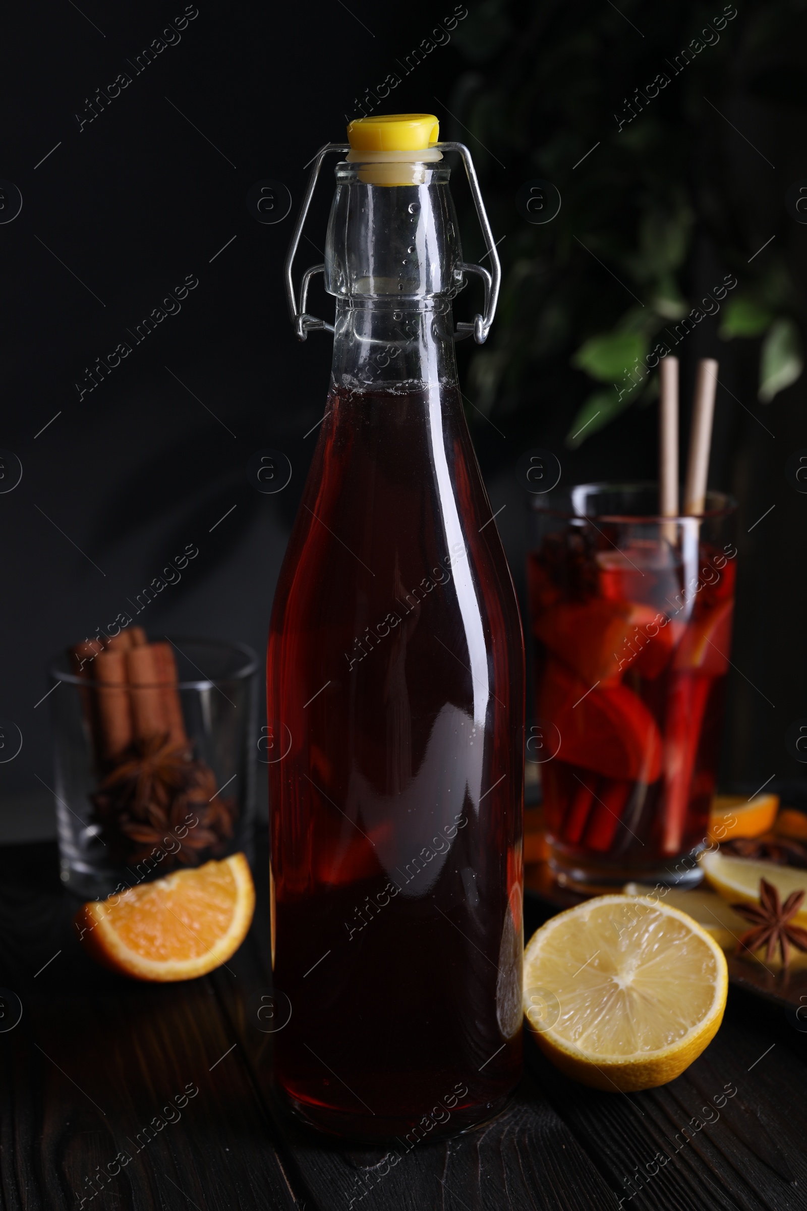 Photo of Bottle of aromatic punch drink and ingredients on wooden table