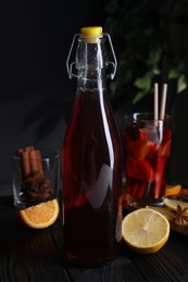 Bottle of aromatic punch drink and ingredients on wooden table