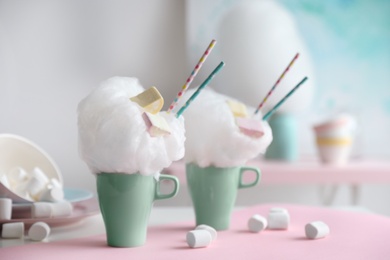 Cups of tasty cotton candy dessert and marshmallow on table, space for text