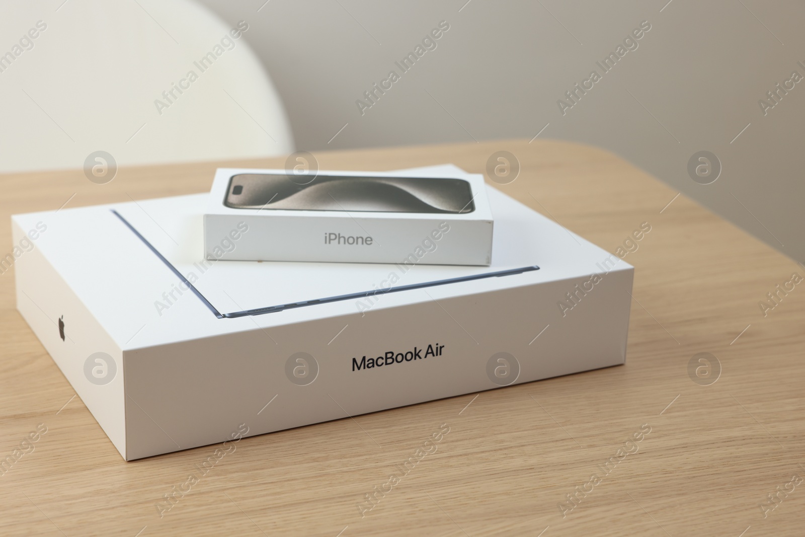 Photo of Leiden, Netherlands - October 6, 2023: Boxes with modern MacBook Air and iPhone 15 Pro Max on wooden table