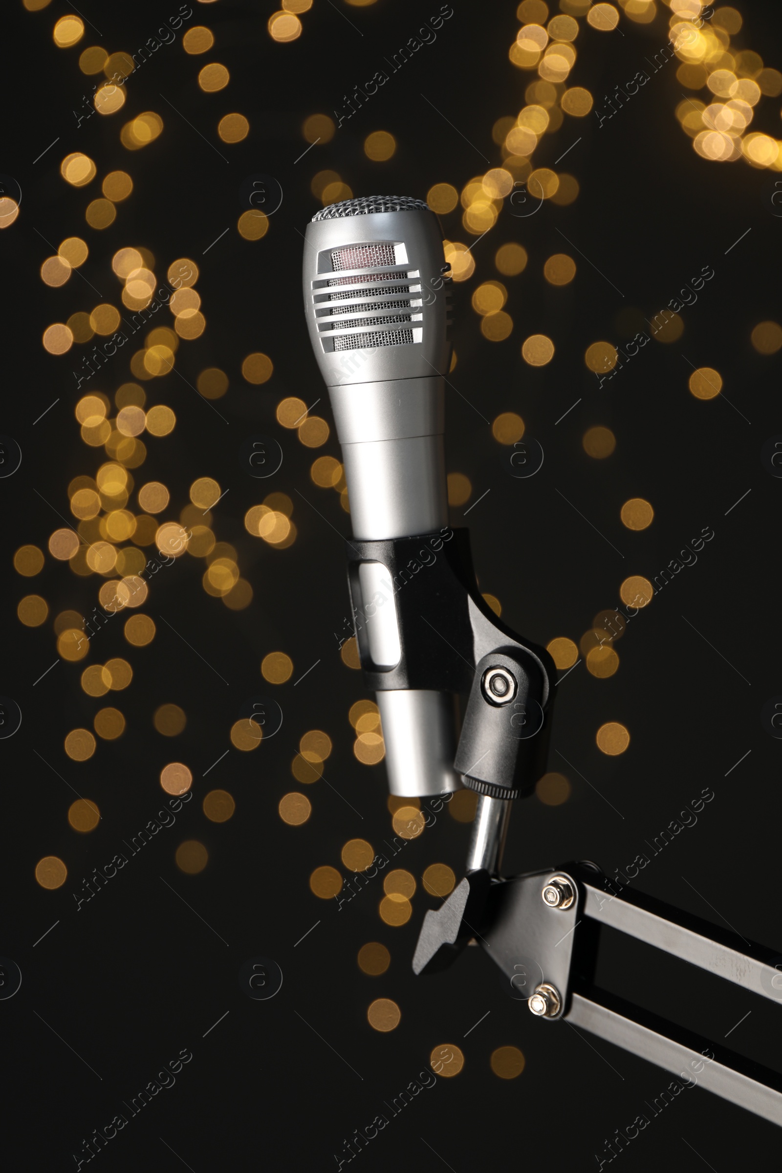 Photo of Stand with microphone against black background with blurred lights. Sound recording and reinforcement