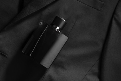 Photo of Luxury men's perfume in bottle on black jacket, top view. Space for text