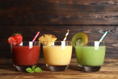 Delicious colorful juices in glasses on wooden table