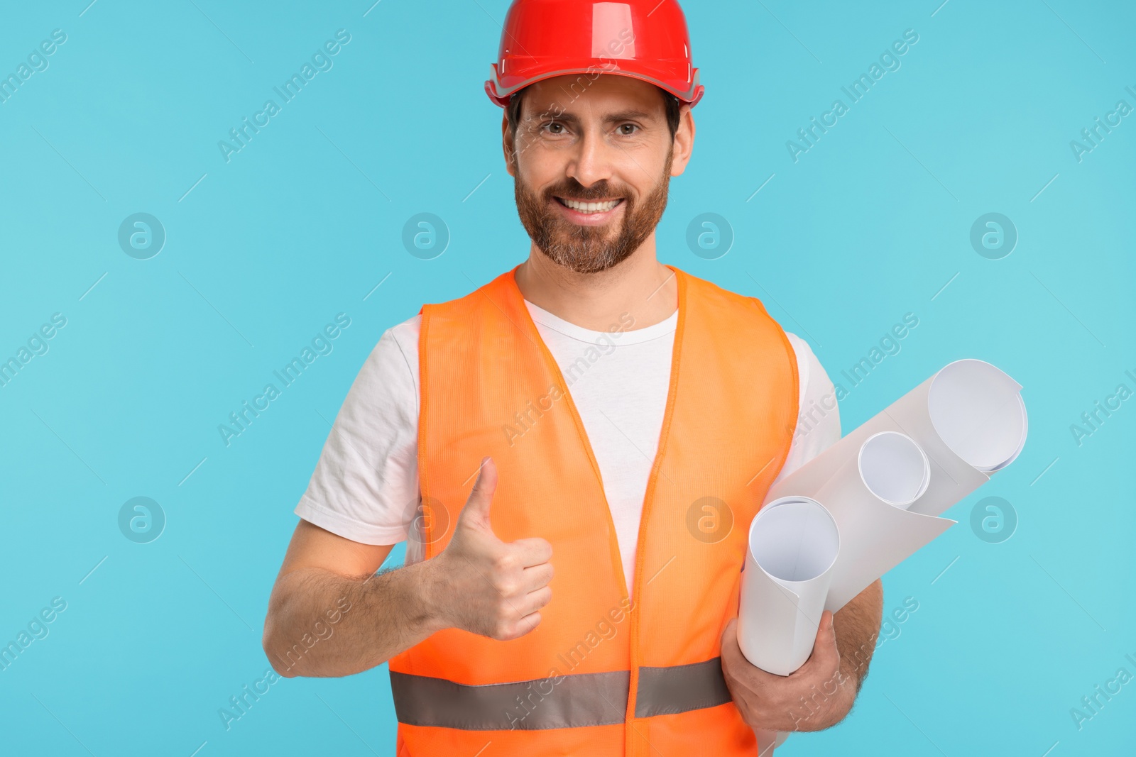 Photo of Architect in hard hat with drafts showing thumbs up on light blue background