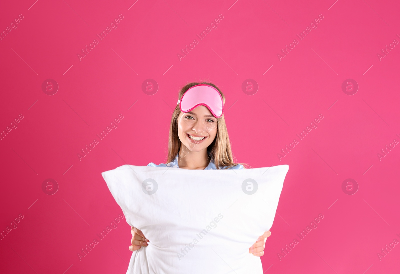 Photo of Young woman with pillow and sleep mask on pink background