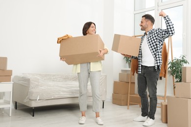 Happy couple with moving boxes in new apartment