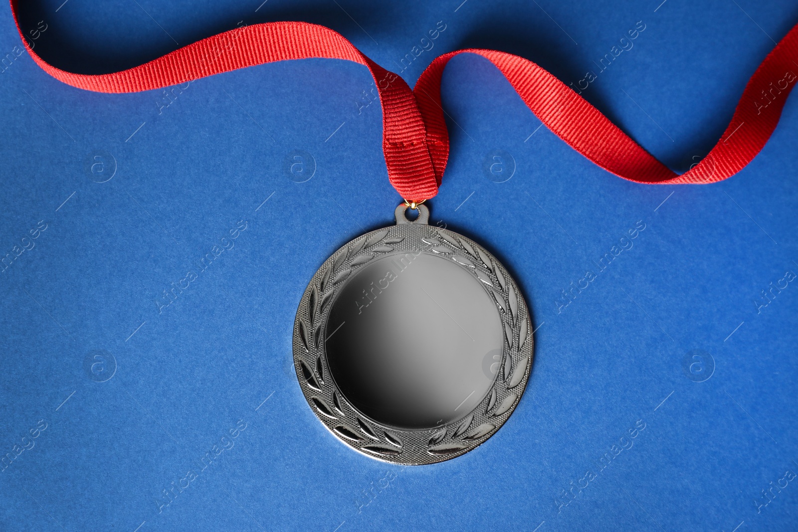 Photo of Silver medal on blue background, top view. Space for design