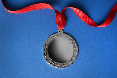 Photo of Silver medal on blue background, top view. Space for design