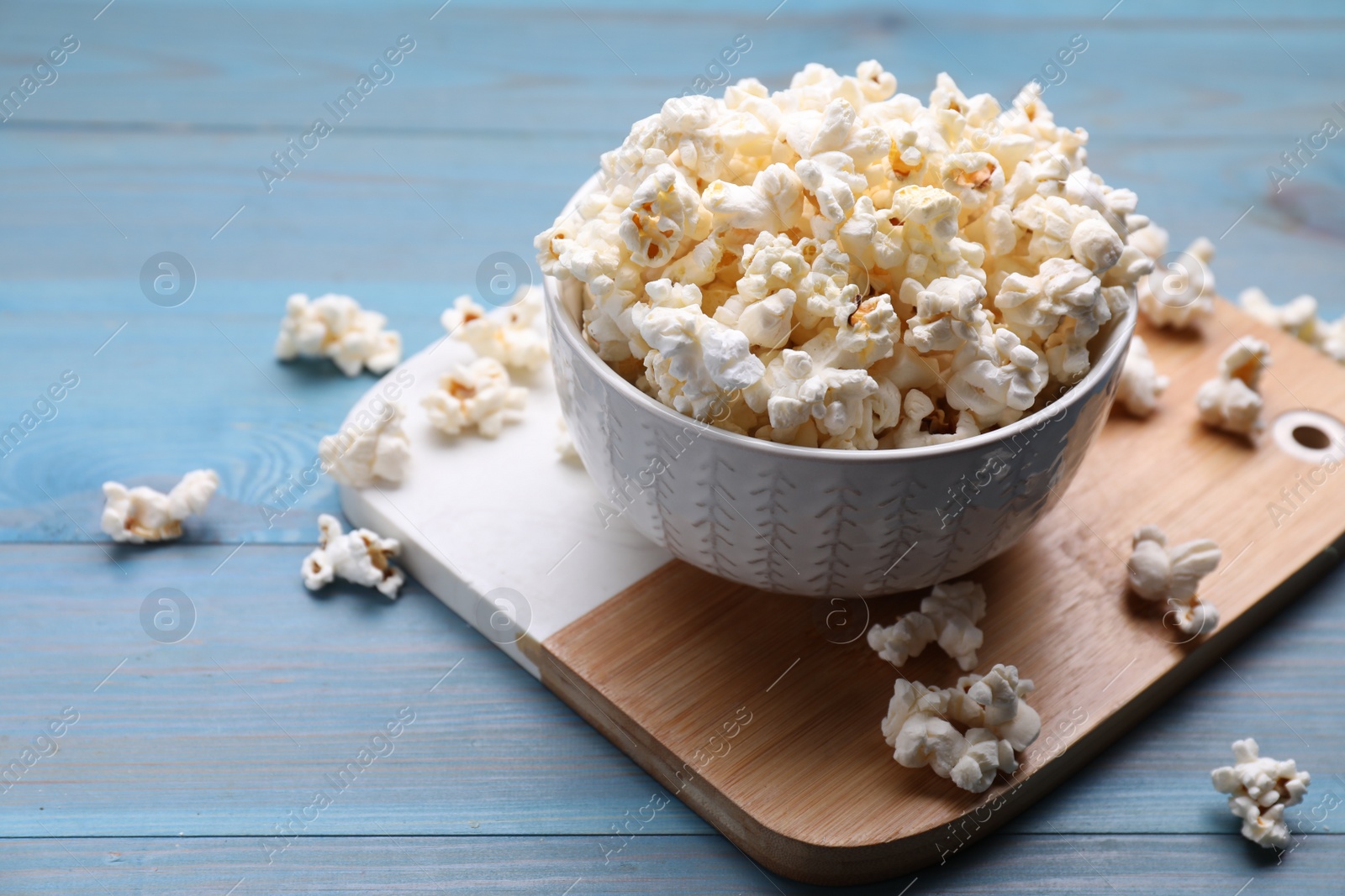 Photo of Tasty popcorn on light blue wooden table