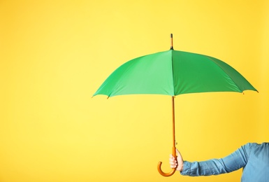 Photo of Woman holding modern colorful umbrella on yellow background, closeup. Space for text