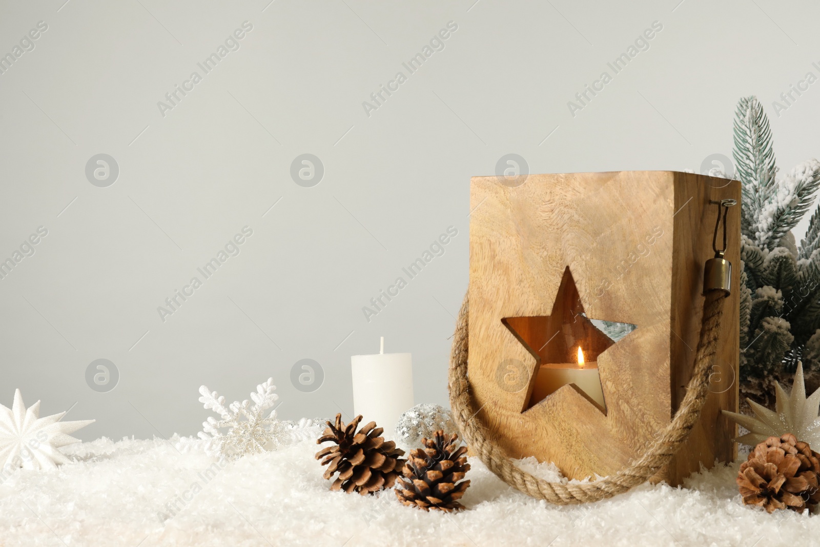 Photo of Composition with wooden Christmas lantern on snow against light grey background, space for text