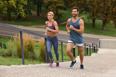 Photo of Healthy lifestyle. Happy couple running up stairs outdoors