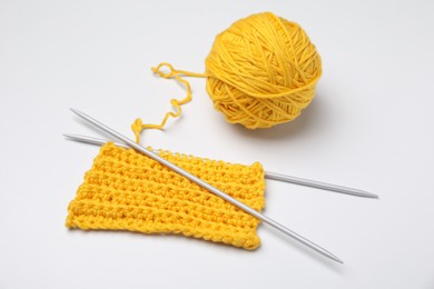 Photo of Soft yellow woolen yarn, knitting and metal needles on white background