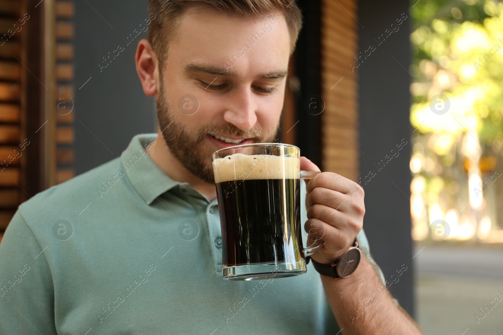 Photo of Handsome man with cold kvass outdoors. Traditional Russian summer drink