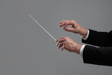 Professional conductor with baton on grey background, closeup