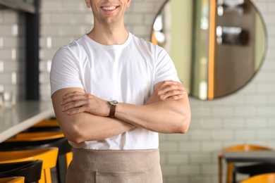 Young waiter in uniform at cafe