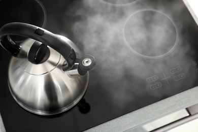 Modern kettle with whistle on stove, above view. Space for text