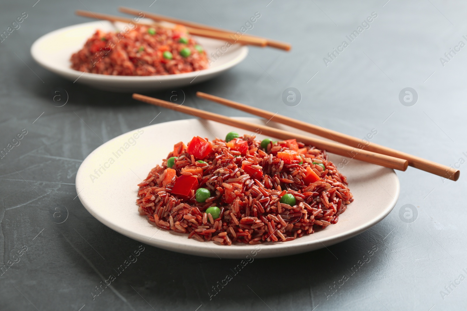 Photo of Tasty brown rice with vegetables on dark grey table