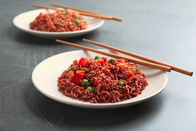 Photo of Tasty brown rice with vegetables on dark grey table