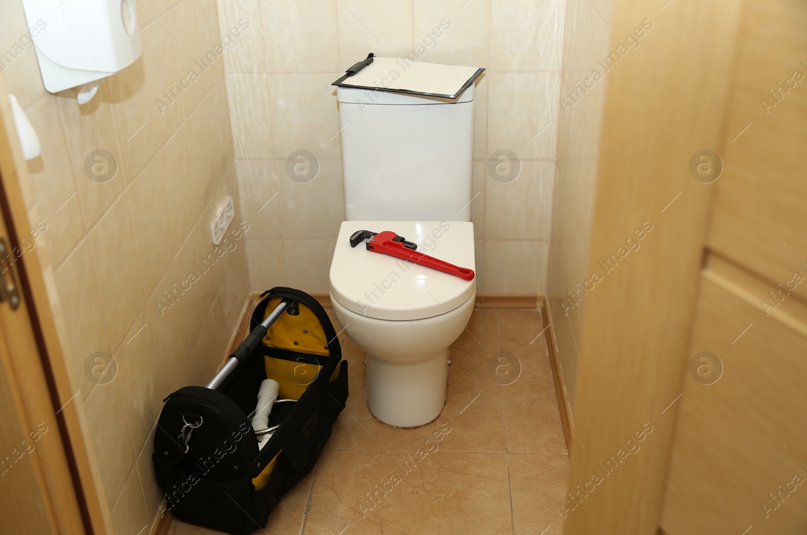 Photo of Pipe wrench and clipboard on toilet indoors