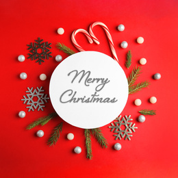 Image of Flat lay composition with text MERRY CHRISTMAS and festive decor on red background