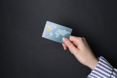 Photo of Woman holding credit card on black background, closeup