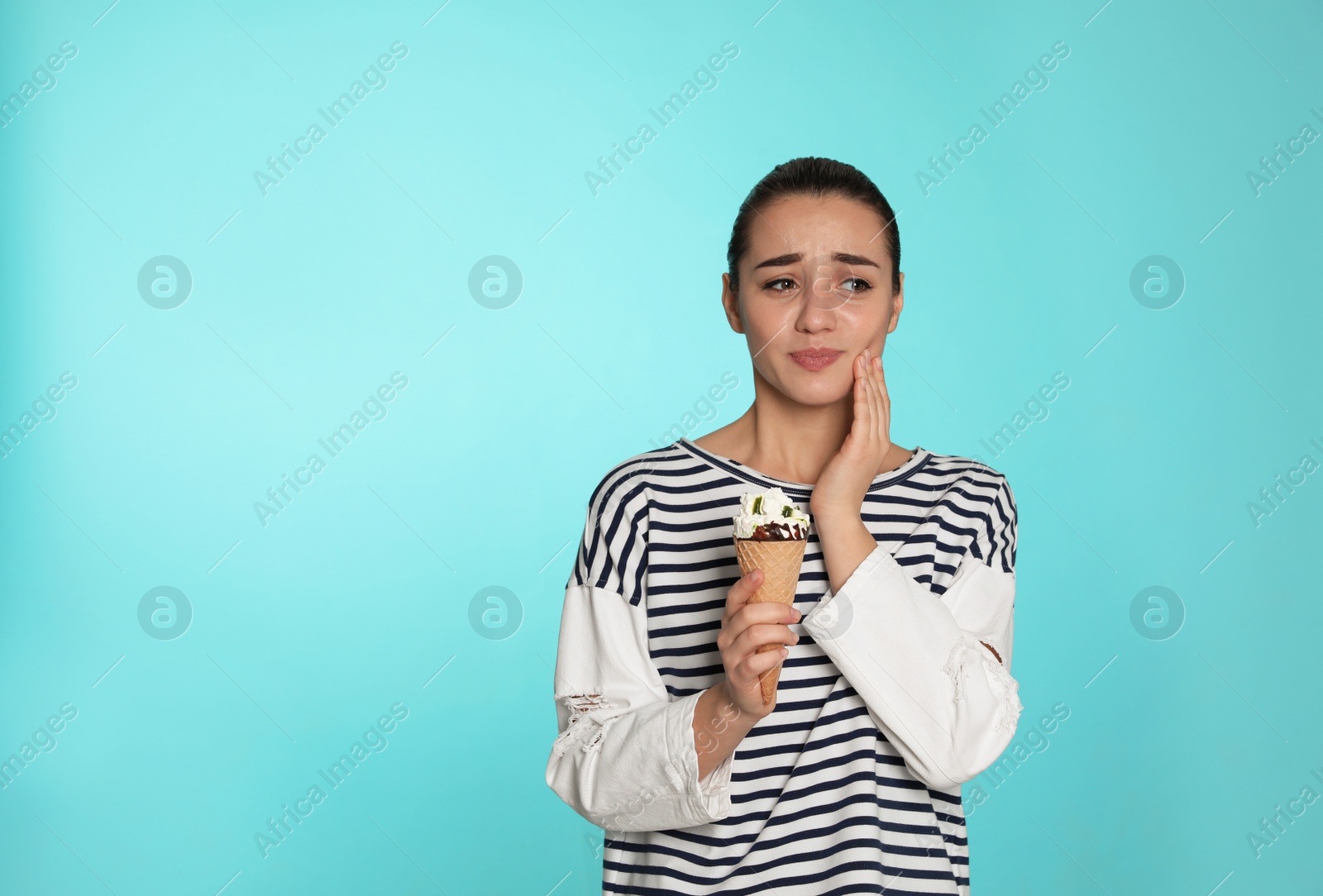 Photo of Emotional young woman with sensitive teeth and ice cream on color background. Space for text