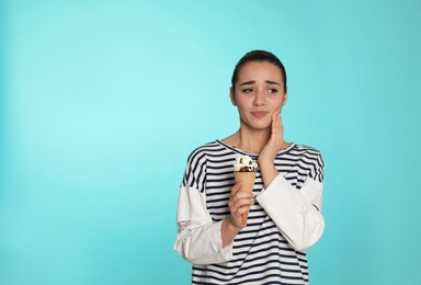 Photo of Emotional young woman with sensitive teeth and ice cream on color background. Space for text