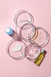 Many Petri dishes and cosmetic products on pink background, flat lay