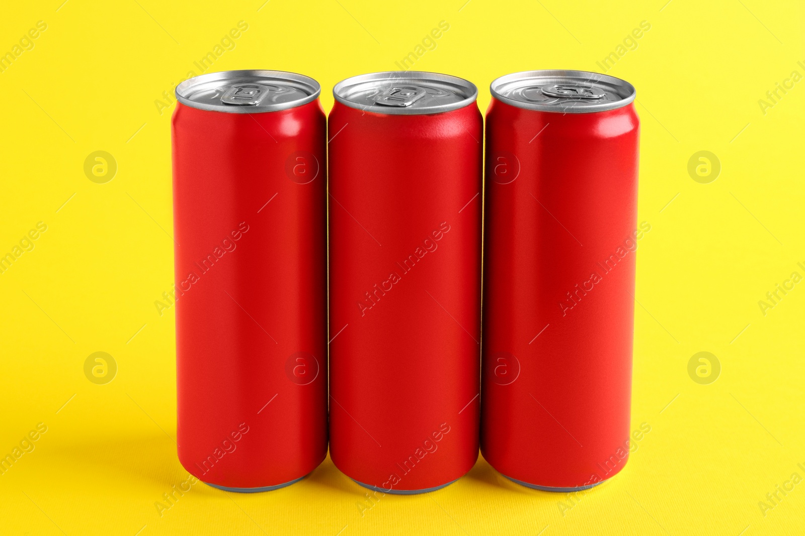 Photo of Energy drinks in red cans on yellow background