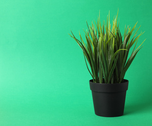 Beautiful artificial plant in flower pot on green background, space for text