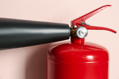 Photo of Fire extinguisher on pink background, closeup view