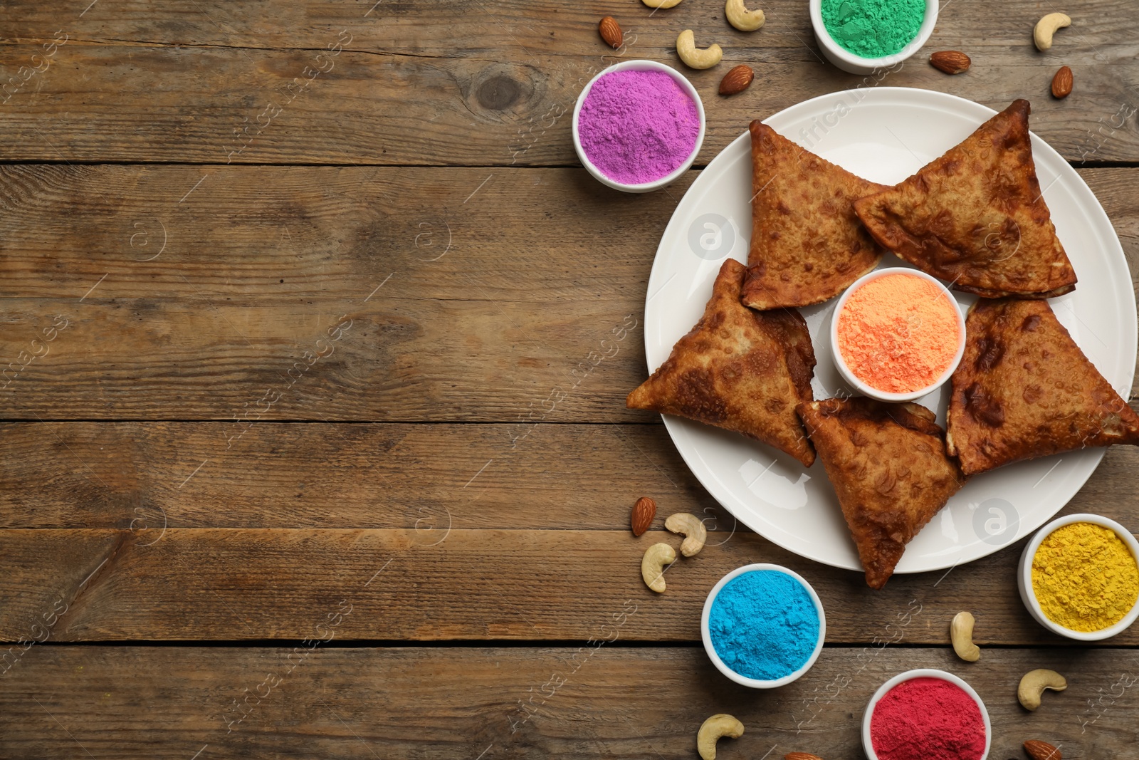 Photo of Traditional Indian food and color powders on wooden table, flat lay with space for text. Holi festival celebration