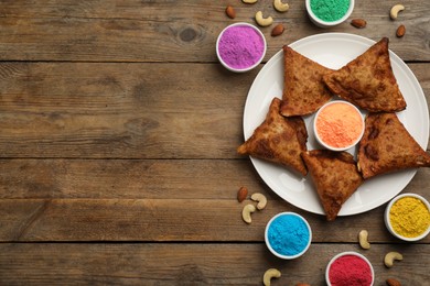 Photo of Traditional Indian food and color powders on wooden table, flat lay with space for text. Holi festival celebration