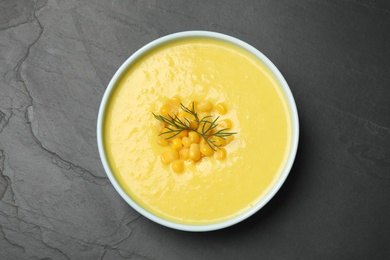 Delicious creamy corn soup on black table, top view