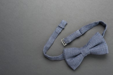 Photo of Stylish blue bow tie on dark background, top view. Space for text