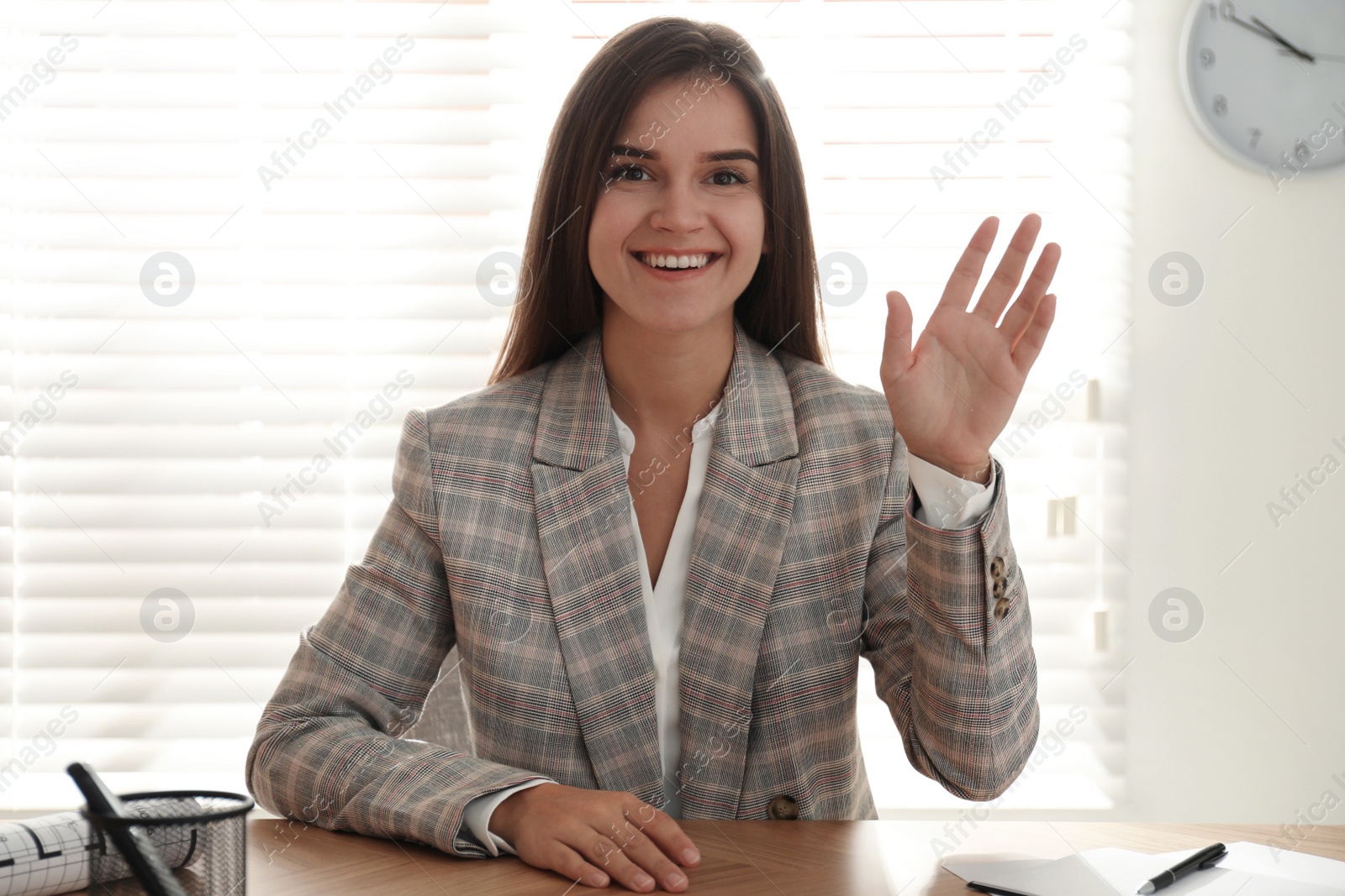 Photo of Young woman talking to her coworkers through video conference in office, view from webcam