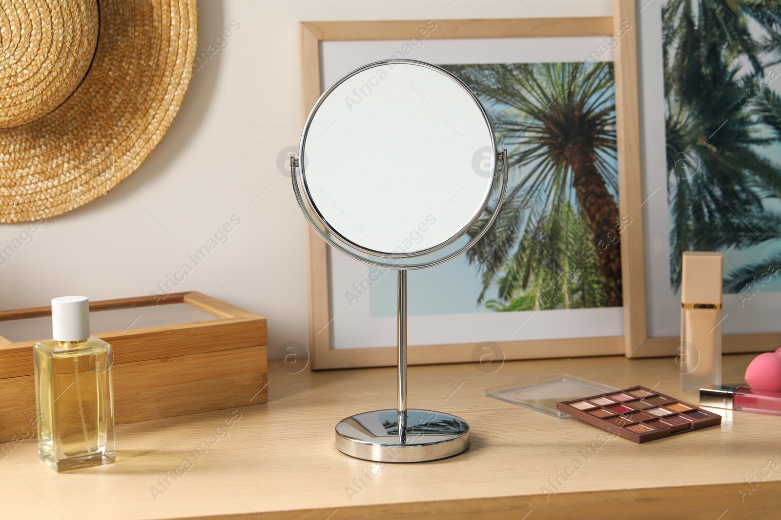 Photo of Mirror, perfume and makeup products on wooden dressing table